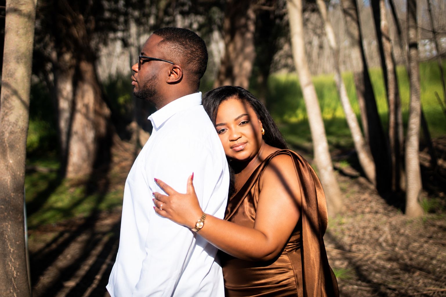 The couple standing close together among the trees