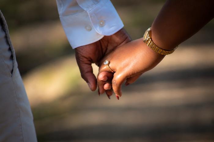 The couple holding hands, engagement ring in view